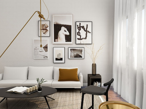 White living room with a three-person couch, a single-person chair, and a collage of artwork on the back wall.