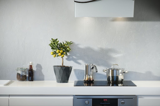 Kitchen countertop in Austin, Texas with lighting fixtures, and an electric stove with a kettle and a stainless steel pot on top of it.