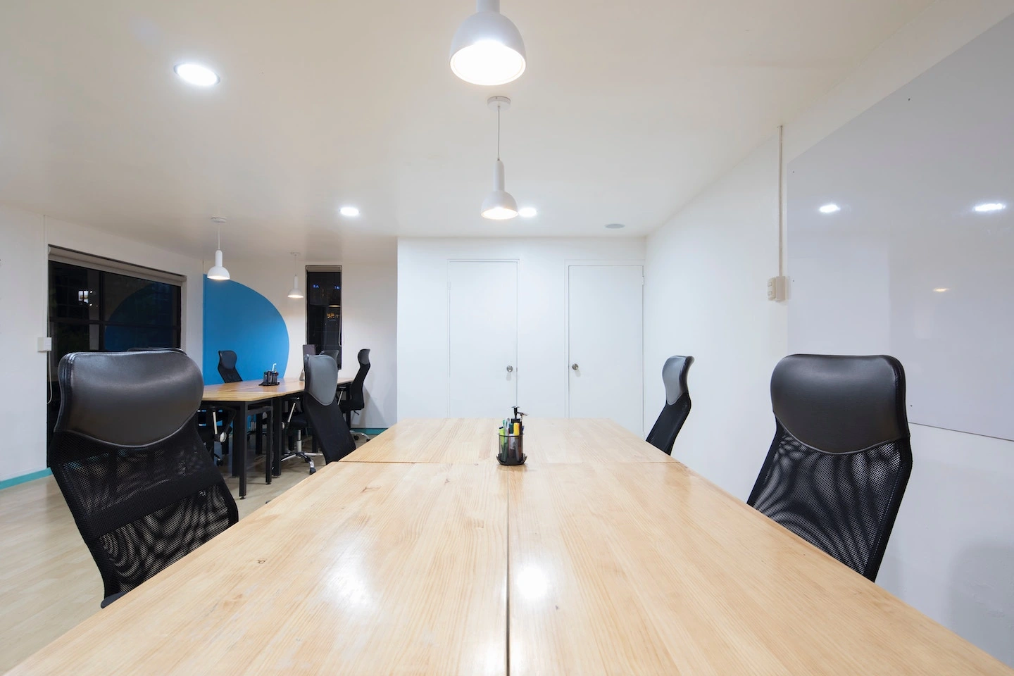 Office meeting room with pendant lighting fixtures and recessed lighting fixtures.