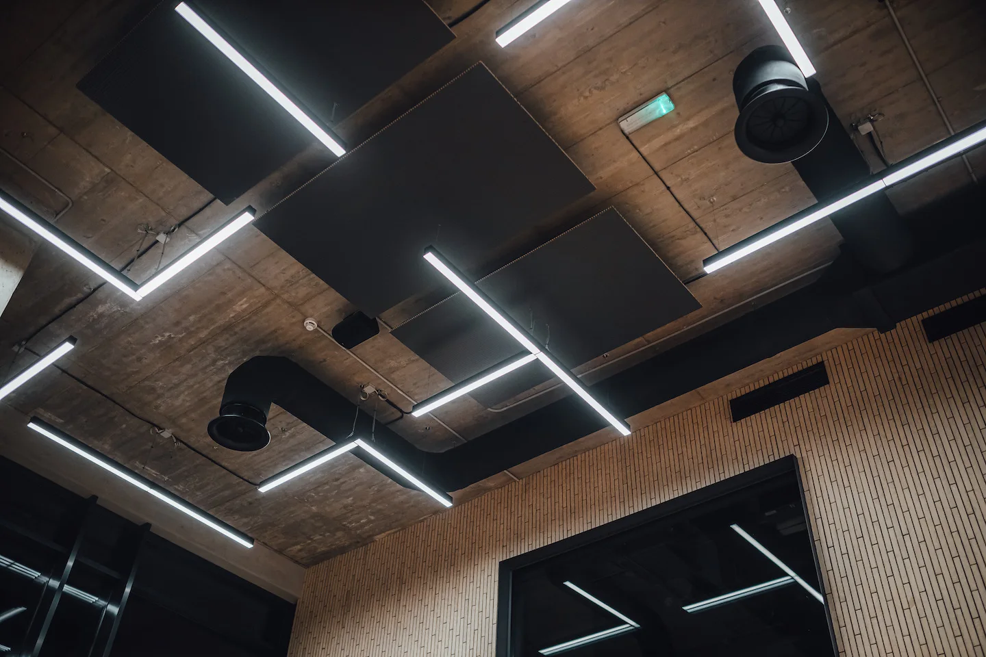 L-shaped and T-shaped LED lighting hanging from the ceiling in commercial space.