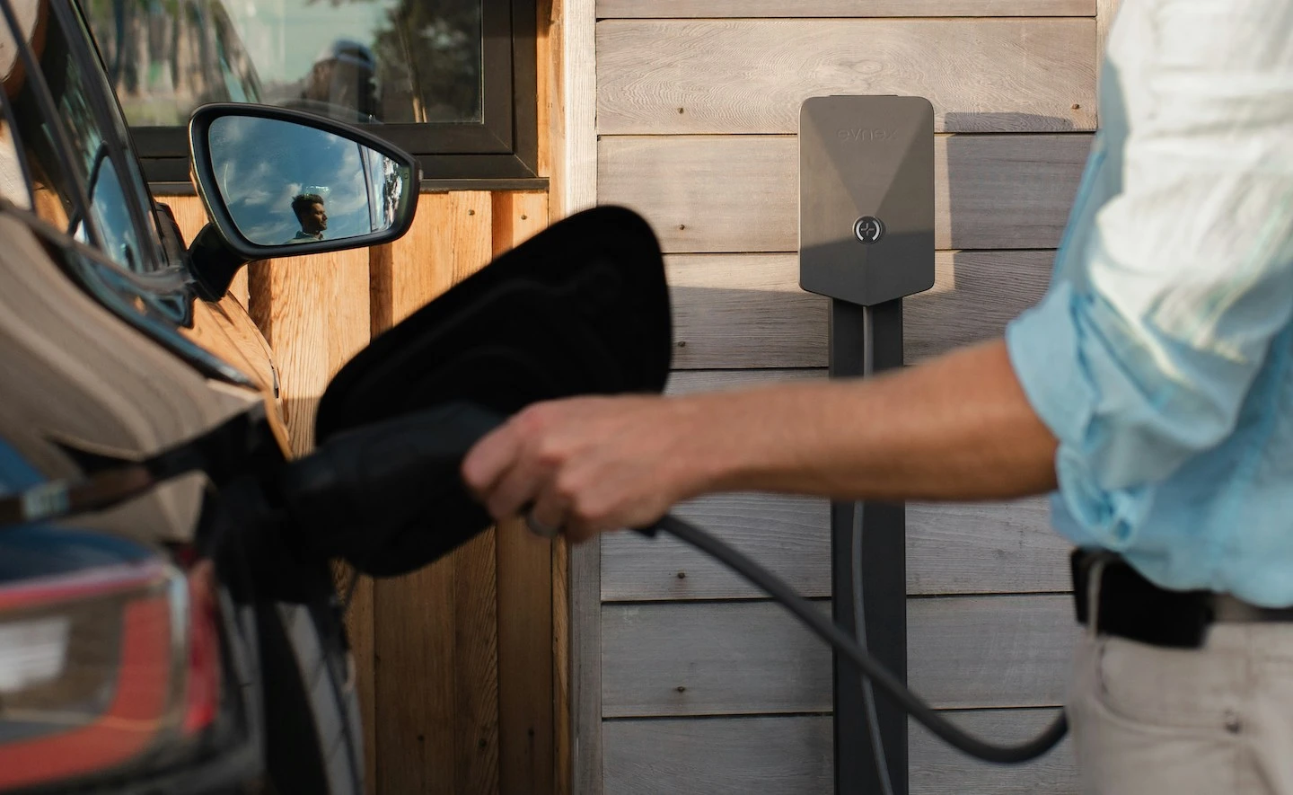 Person plugging electrical vehicle in to charge.