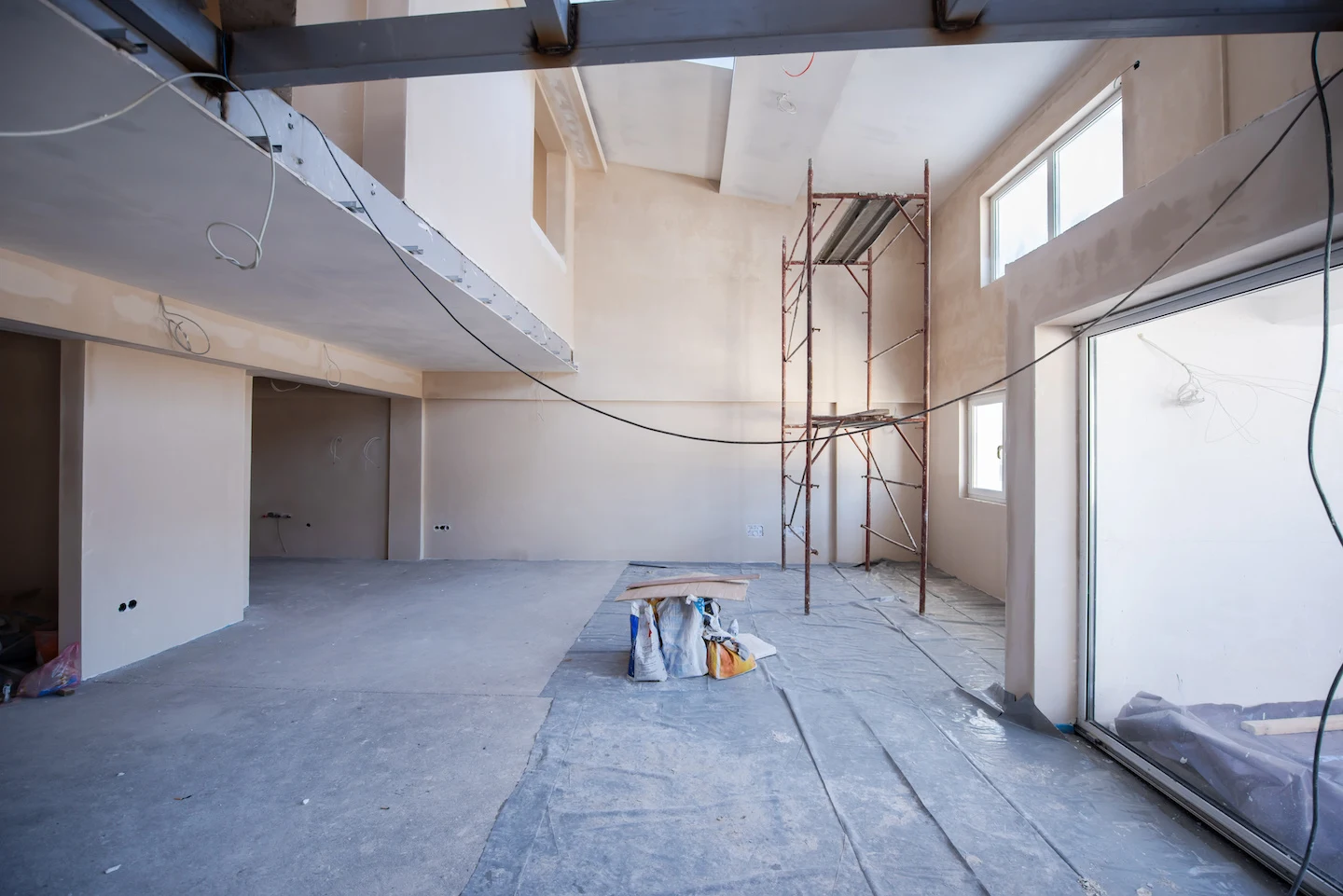 Interior of building under construction with scaffolding and loose wires.