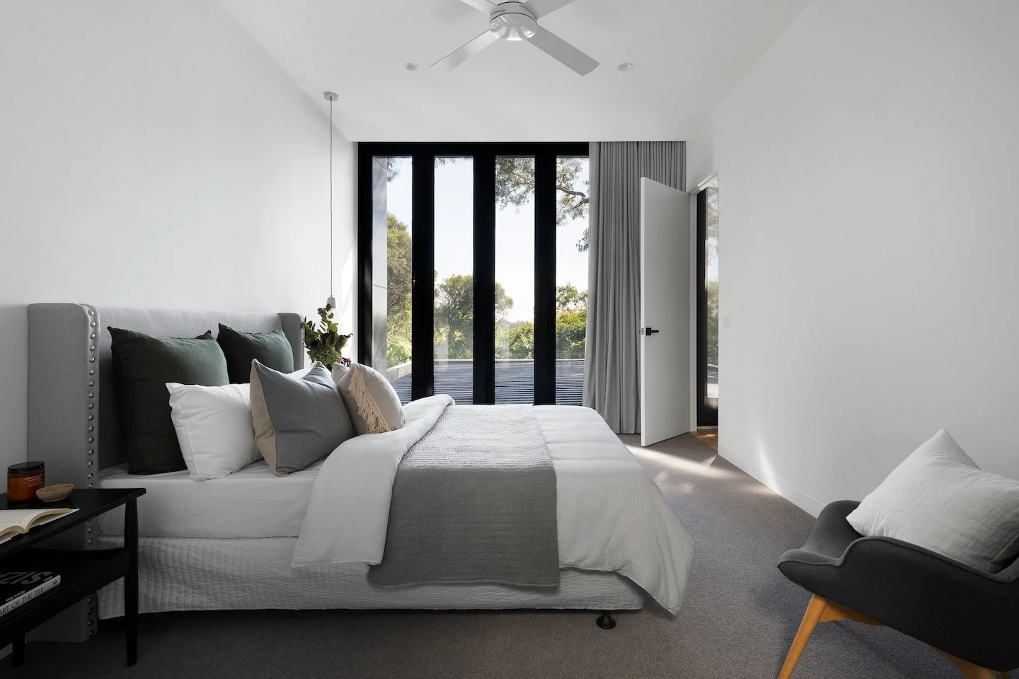 Bedroom in Austin with floor to ceiling windows, long pendant light, and ceiling fan.