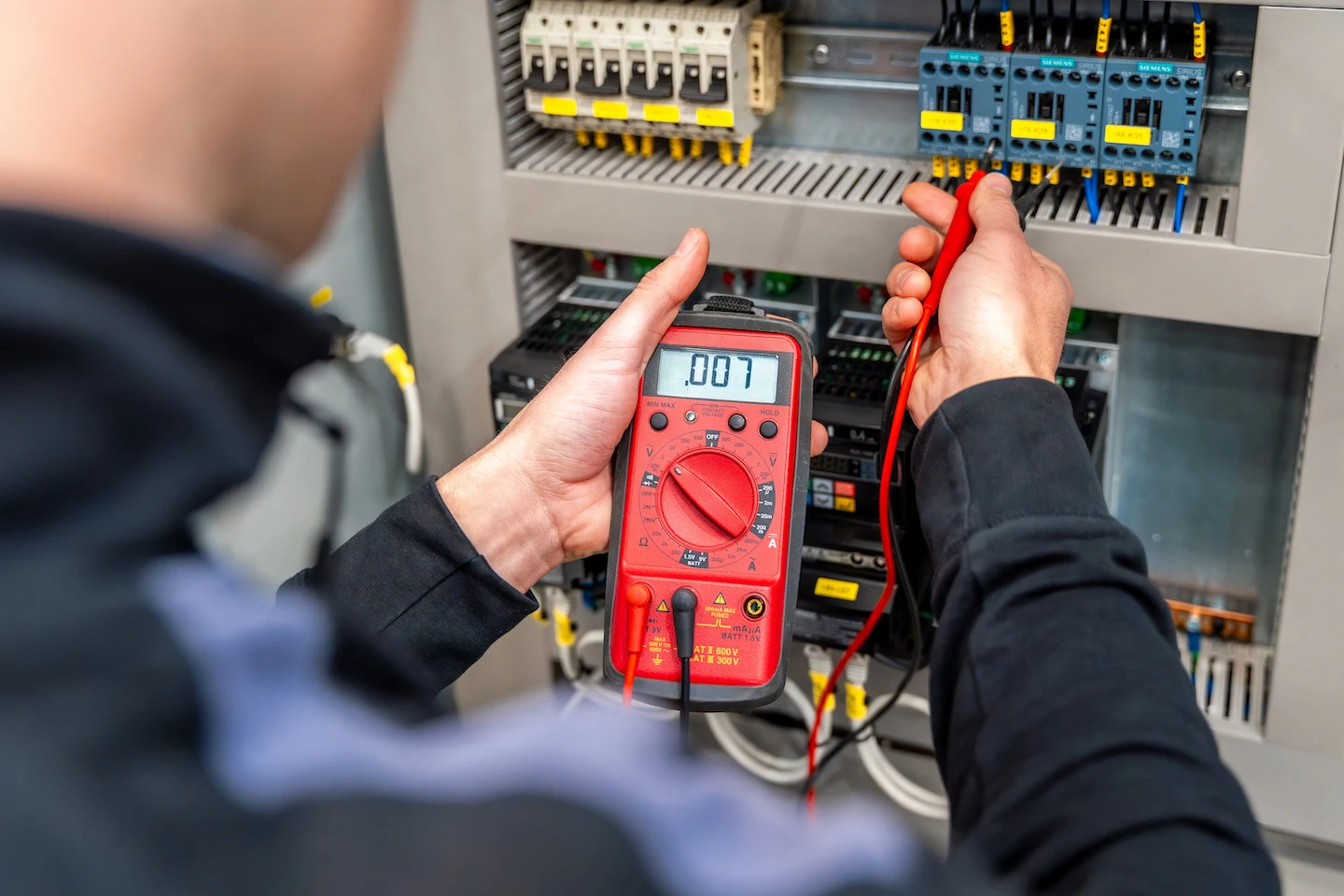 Electrician measuring electrical panel.