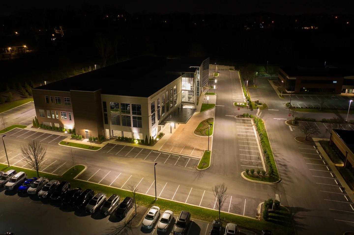 Office building parking lot at night with pole lighting and canopy lighting.